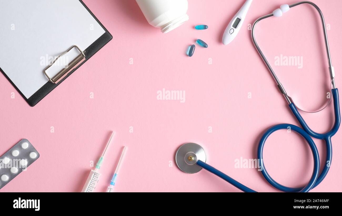 Medical equipment and instruments on pink background. Frame of medical clipboard, stethoscope, pills, thermometer, syringes. Top view doctors table. H Stock Photo