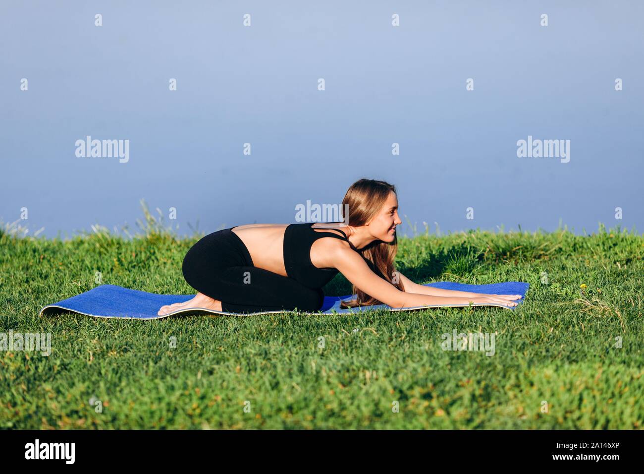 Girl sitting in relax pose on yoga mat outdoor . Side view- Image Stock ...