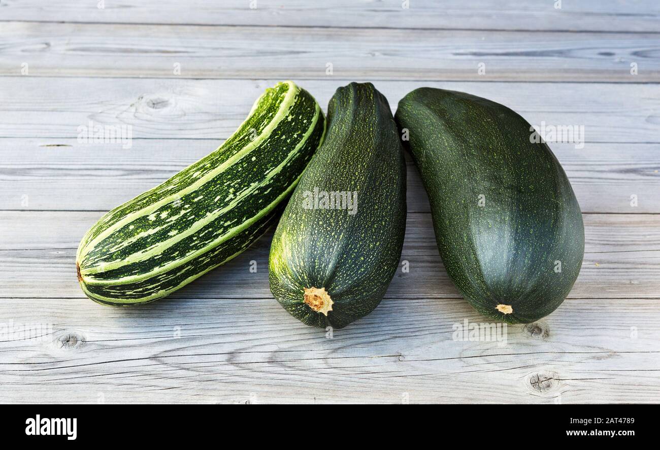 Zucchini. Fresh zucchini or courgette on wooden background. Heap of green vegetable marrow. Stock Photo