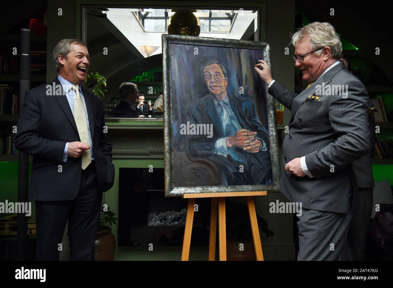 Nigel Farage stands beside a portrait of himself titled Mr Brexit by artist Dan Llywelyn Hall, with Comedian Jim Davidson (right), at L'Escargot Restaurant in London. Stock Photo
