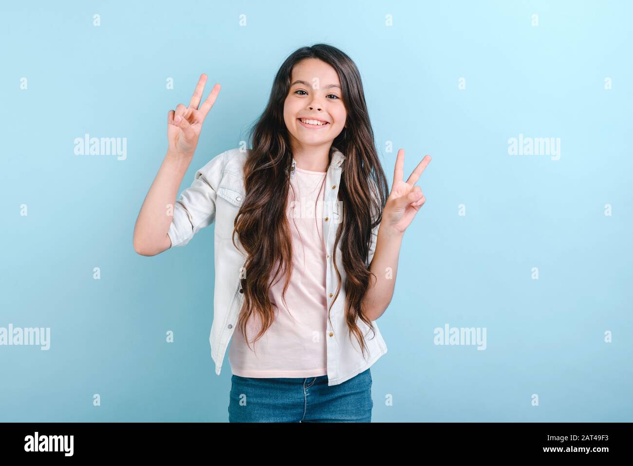 Free Photo  Young sporty woman winking and smiling showing two fingers  standing over purple wall