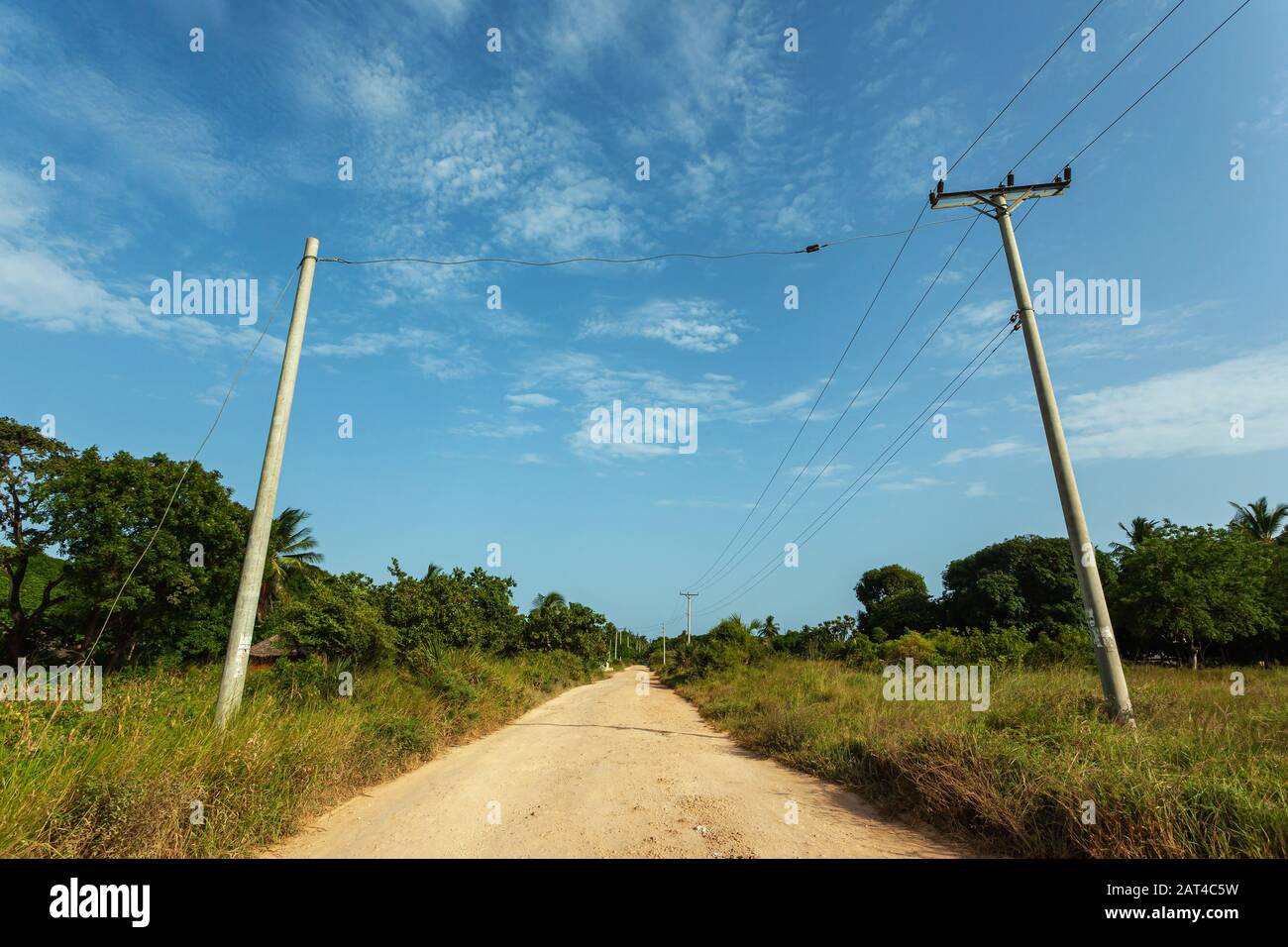 Dry empty road on a bright day in rural Kenya, with electricity poles by the road Stock Photo
