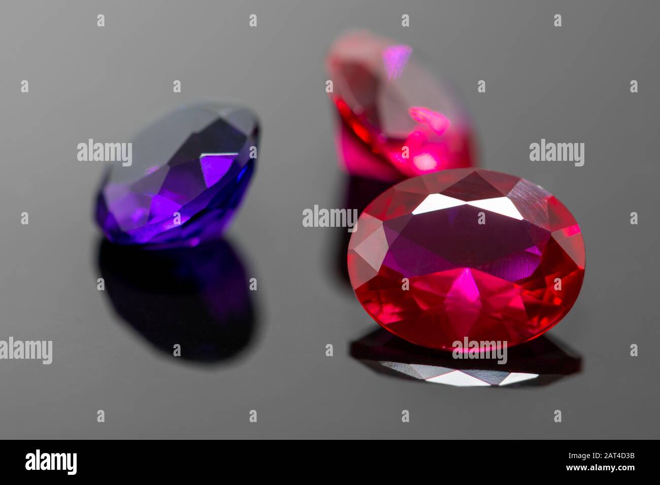 Macro view of oval red ruby gemstone with polishing streaks on black  reflective surface with blurred red ruby and purple amethyst in background  with c Stock Photo - Alamy
