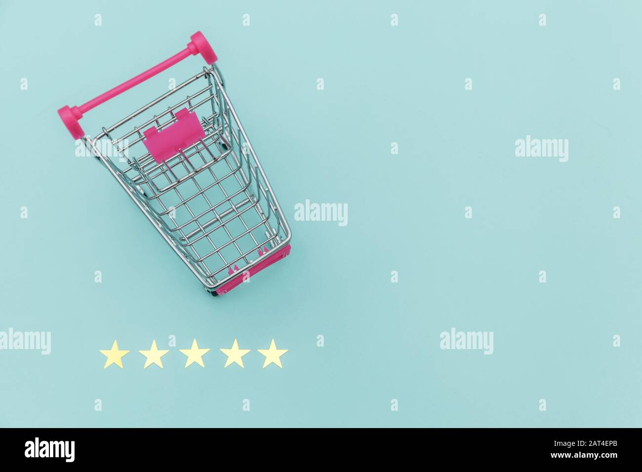 Small supermarket grocery push cart for shopping toy with wheels and 5 stars rating isolated on pastel blue background. Retail consumer buying online assessment and review concept Stock Photo