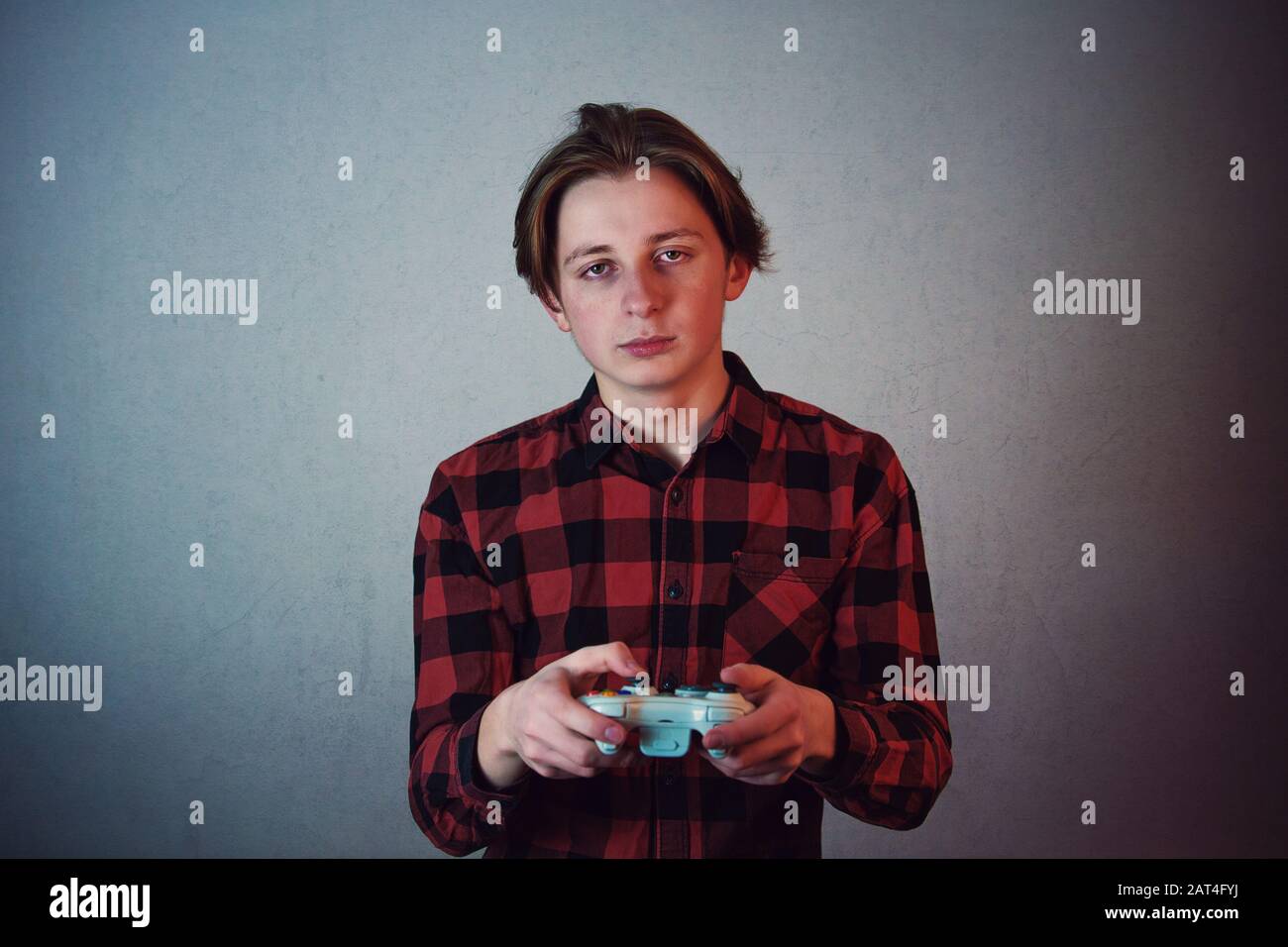 Exhausted teenage guy playing video games isolated on grey wall