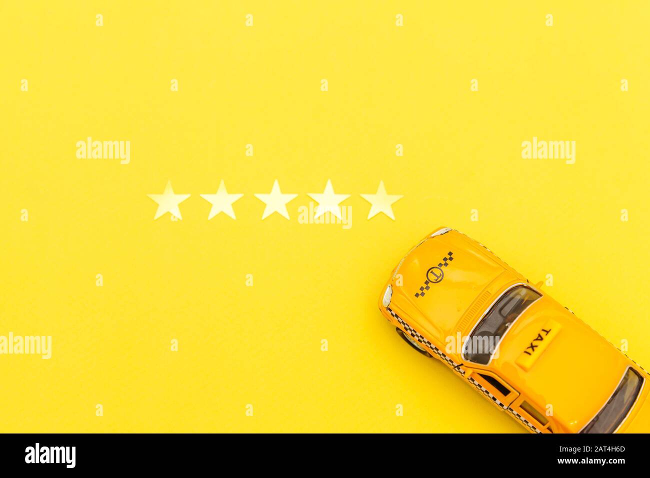 Yellow toy car Taxi Cab and 5 stars rating isolated on yellow background. Smartphone application of taxi service for online searching calling and booking cab concept. Taxi symbol. Copy space Stock Photo