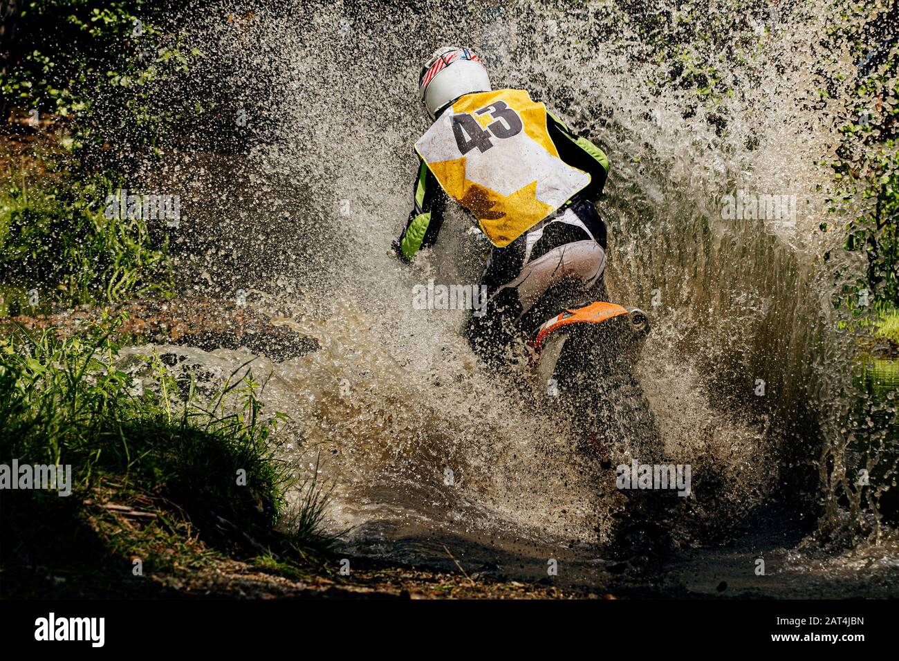 back rider enduro motorcycle riding puddle of water and mud, splashes and drops Stock Photo