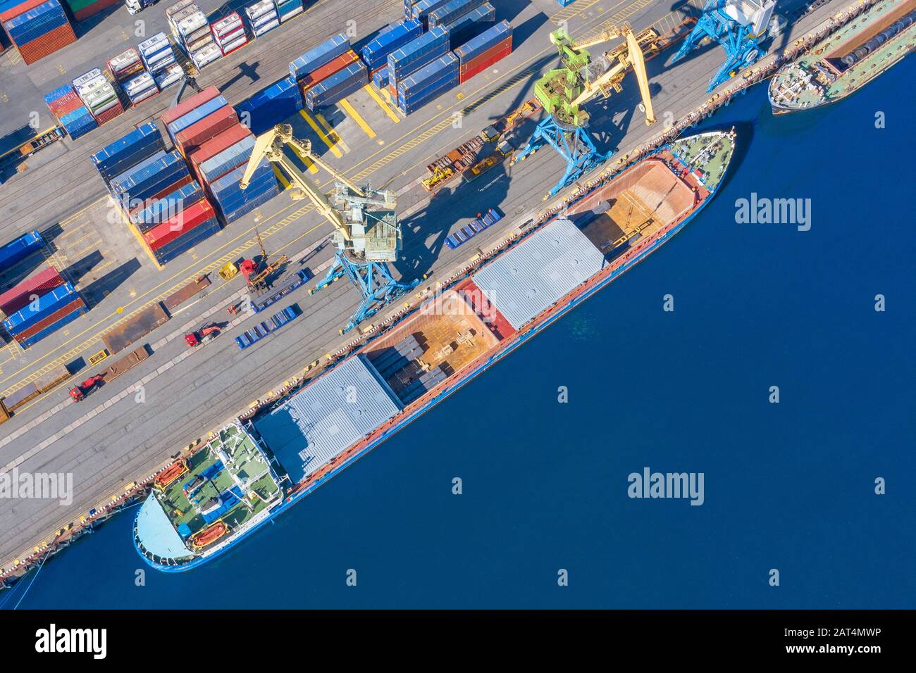 Aerial top view huge cargo ship moored at the pier at the port, loading