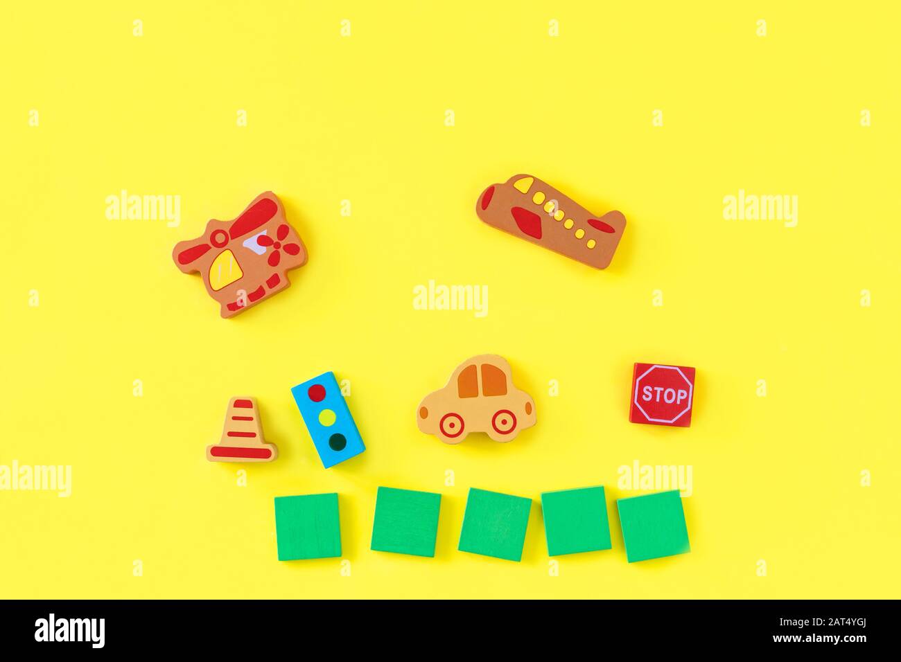 Colorful developing wooden blocks and handmade cars on yellow background. Natural, eco-friendly wooden toys for children. Top view. Flat lay. Copy space. Stock Photo