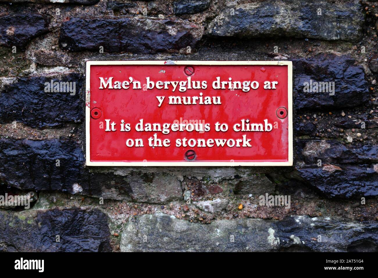 Sign in Welsh and English warning people not to climb on stone walls, Coity Castle, Mid Glamorgan, Wales, UK Stock Photo