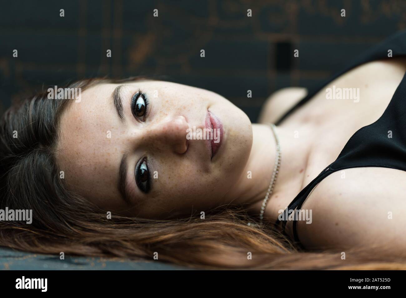 Headshot of an 18 year old cute girl, lying on a coutch and looking shy in the camera Stock Photo