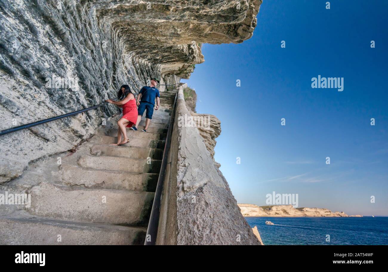 Visitors descending the stairs at Escalier du roi d'Aragon in limestone cliff over Strait of Bonifacio in Bonifacio, Corse-du-Sud, Corsica, France Stock Photo