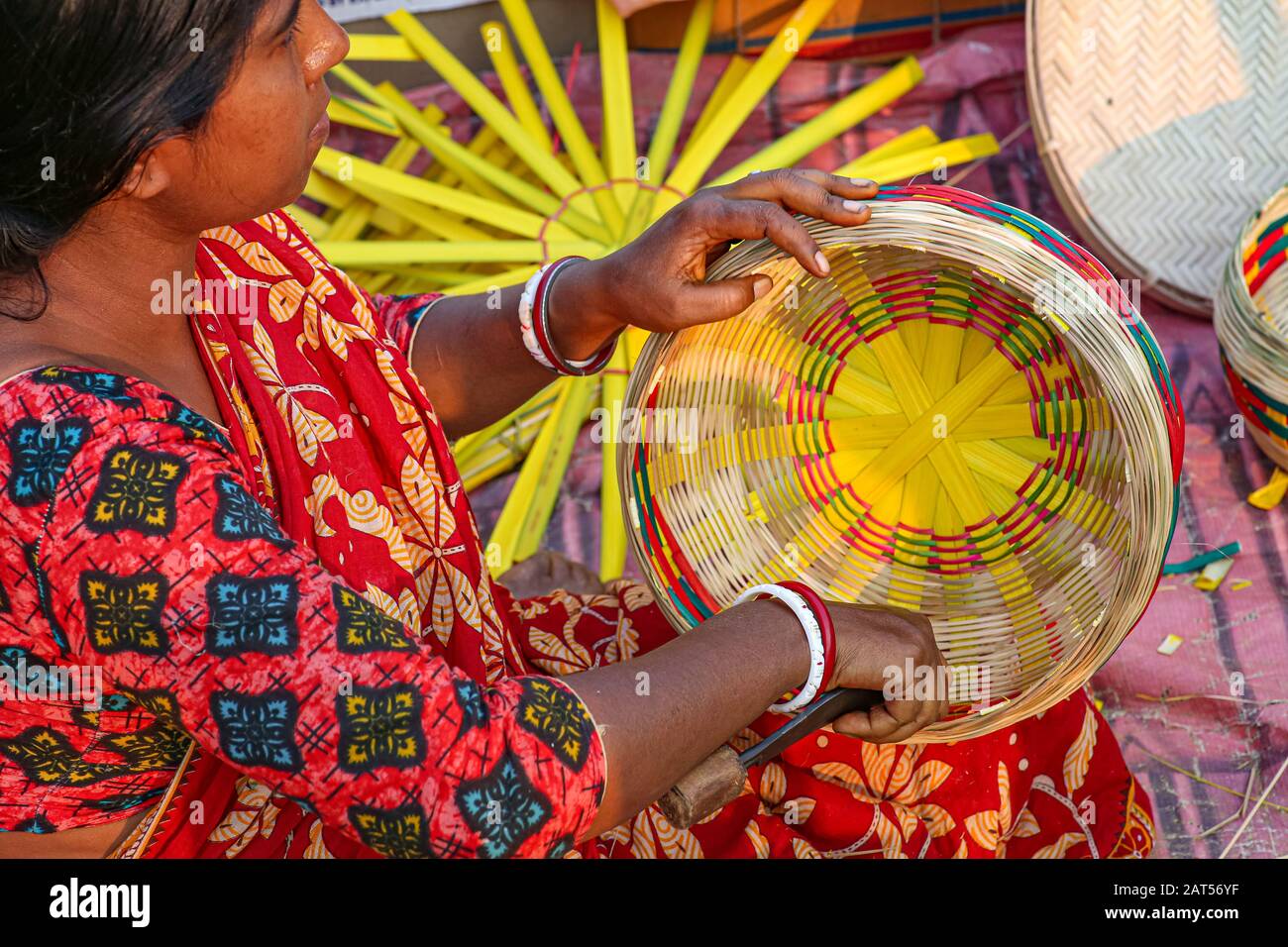 Rural woman hand weaving a basket from bamboo cane strands at a handicraft fare at Kolkata Stock Photo