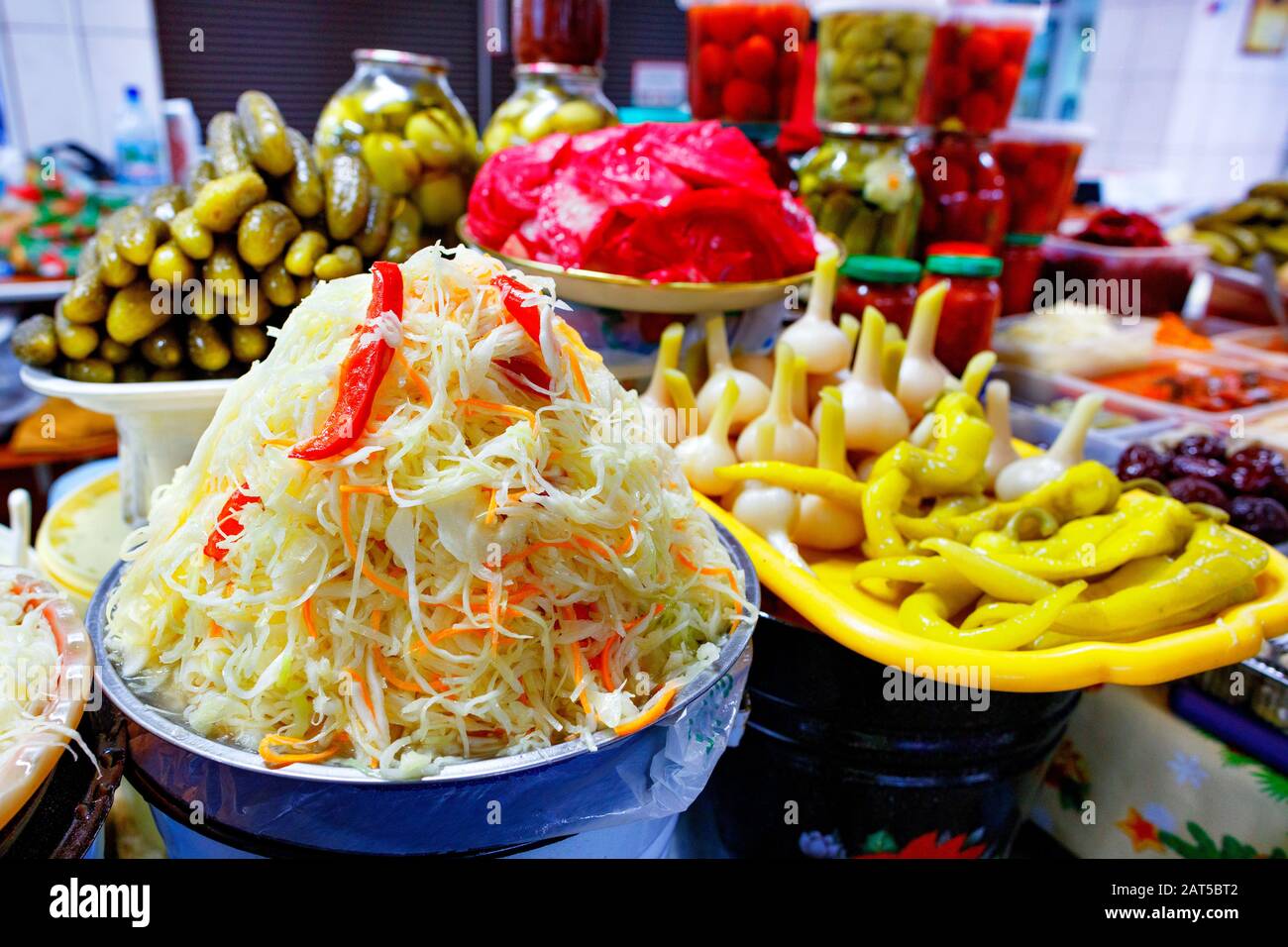 Pickled vegetables, hill salad with sauerkraut, carrots and sweet peppers on the background of other fermented vegetables in the blur. Stock Photo