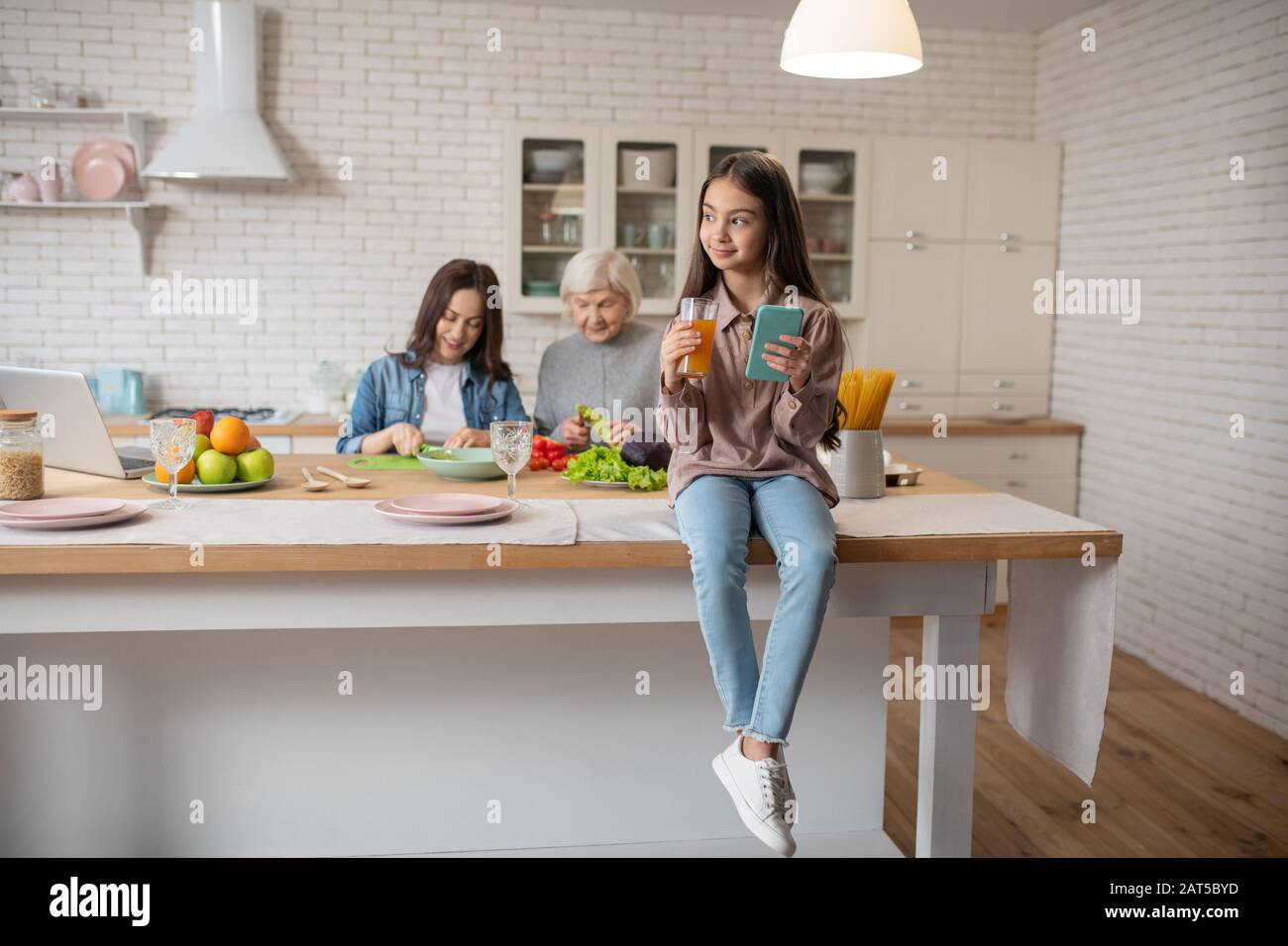 Happy little girl sitting on the kitchen table Stock Photo - Alamy