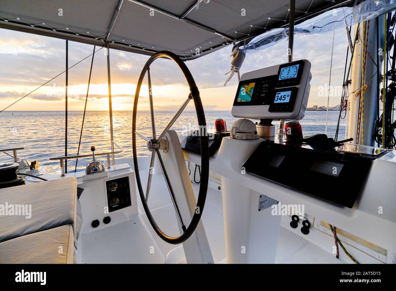 Idyllic scenery glowing sun down Ocean calm water view from catamaran flybridge open deck, modern luxury yacht equipped with navigation dashboard devi Stock Photo