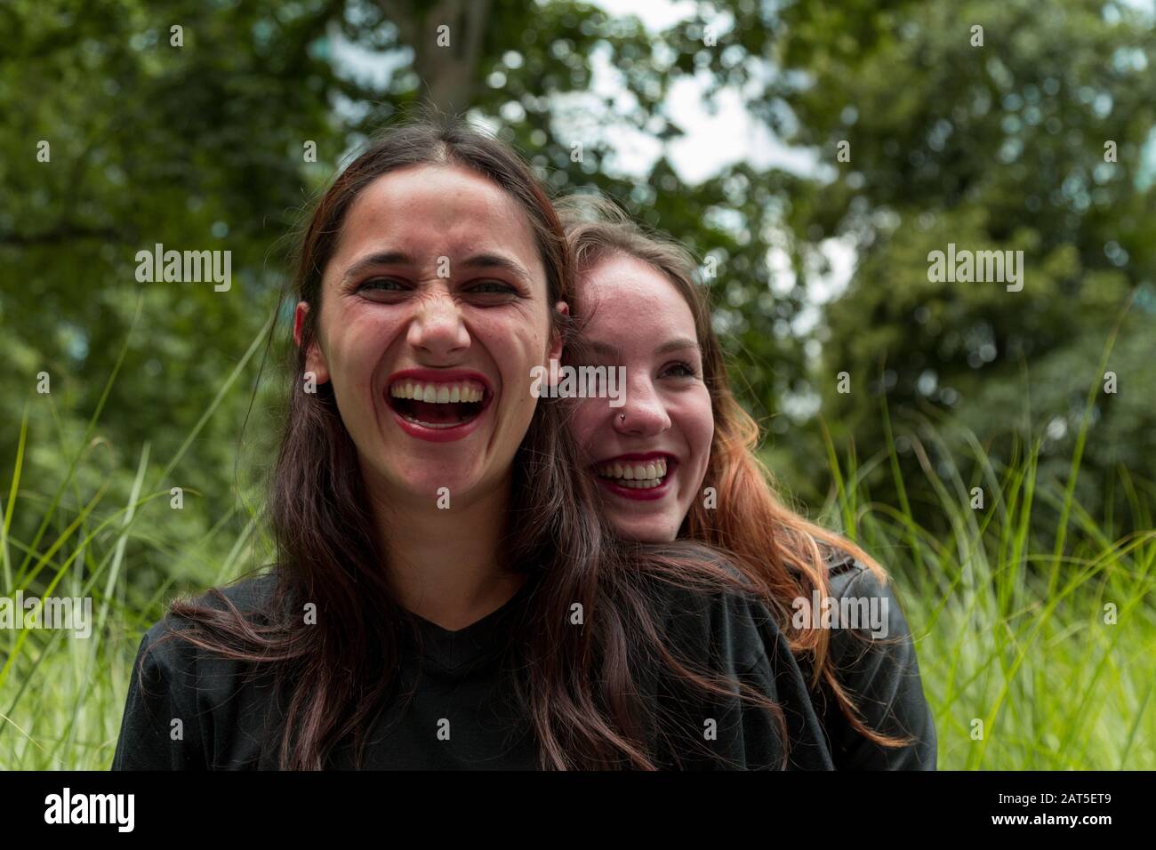 Hugging Friends Different Races Two girlfriends of different races laughing with one hugging the other ...