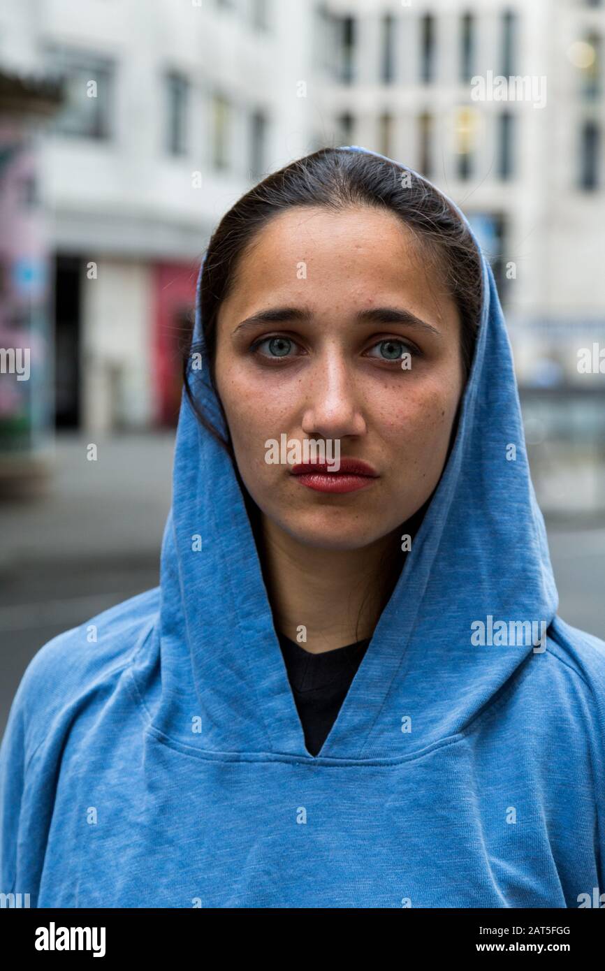 Young woman of middle eastern descent wearing blue hooded sweater. Looking at camera. Stock Photo