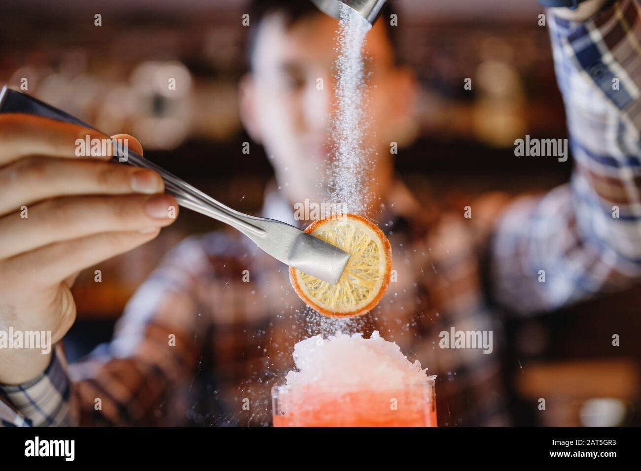 Barman mixes blue cocktail show with colorful alcoholic and with icing sugar orange bar counter Stock Photo