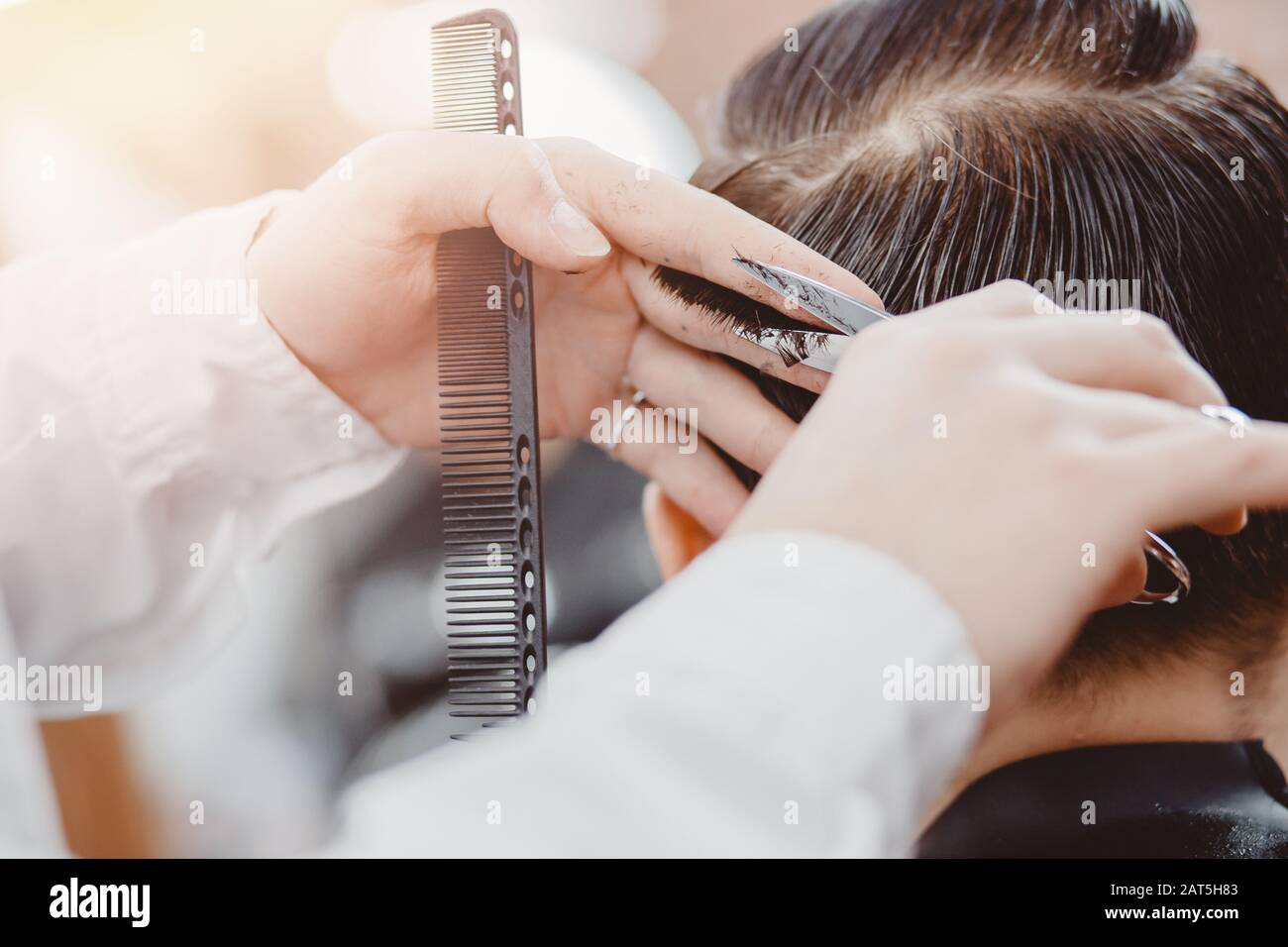 Barber master hairdresser does hairstyle and style with scissors and