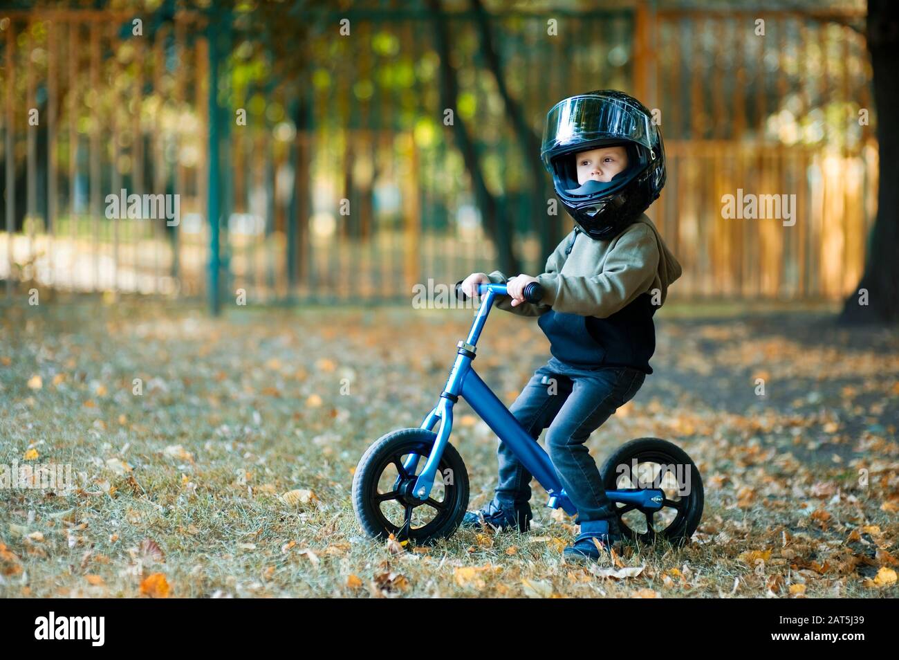 the kid on the scooter is too much protected by a large motorcycle helmet Stock Photo Alamy