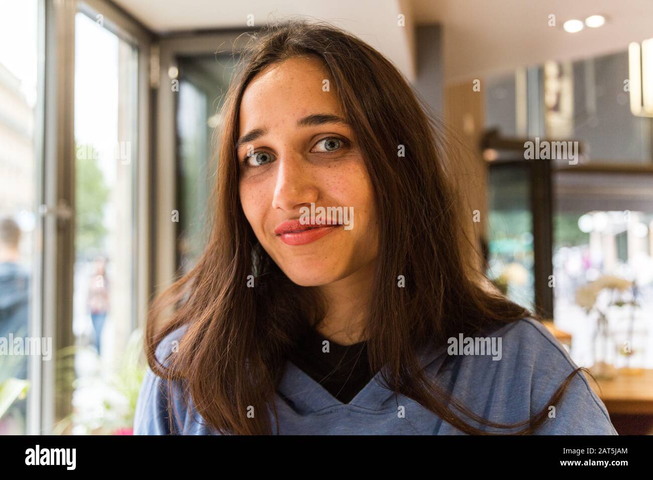 Portrait of mixed race Indian girl sitting in coffee shop looking at the camera. Medium close up. Stock Photo