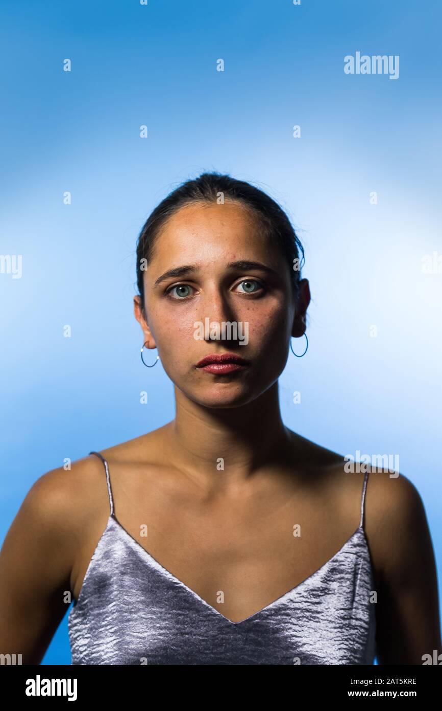 Studio portrait of young Indian woman on sky blue background. Medium close up. Looking at camera. Stock Photo