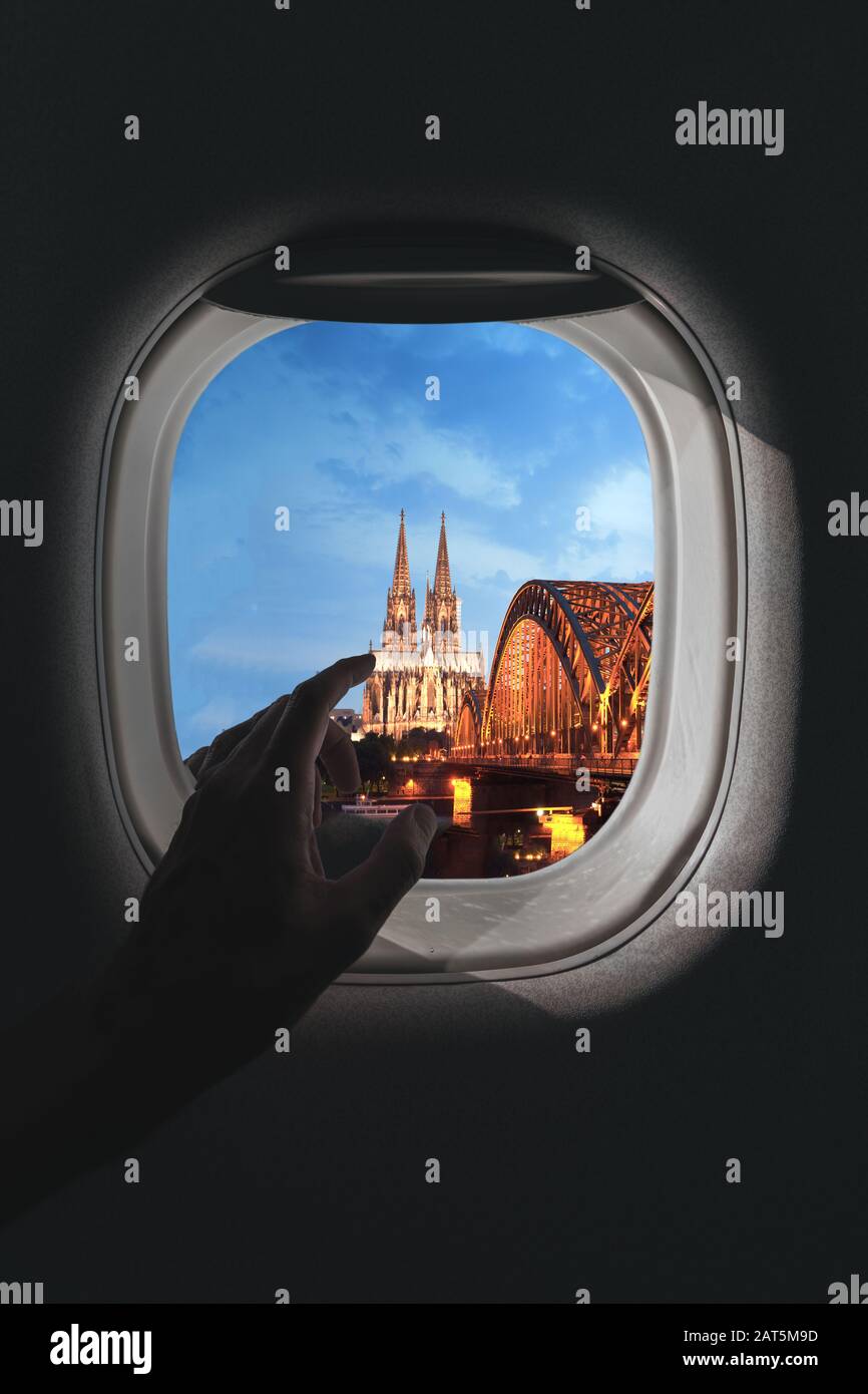 Airplane window with a aerial panorama of Cologne, Germany and Cologne Cathedral with a bridge in the evening during a flight Stock Photo
