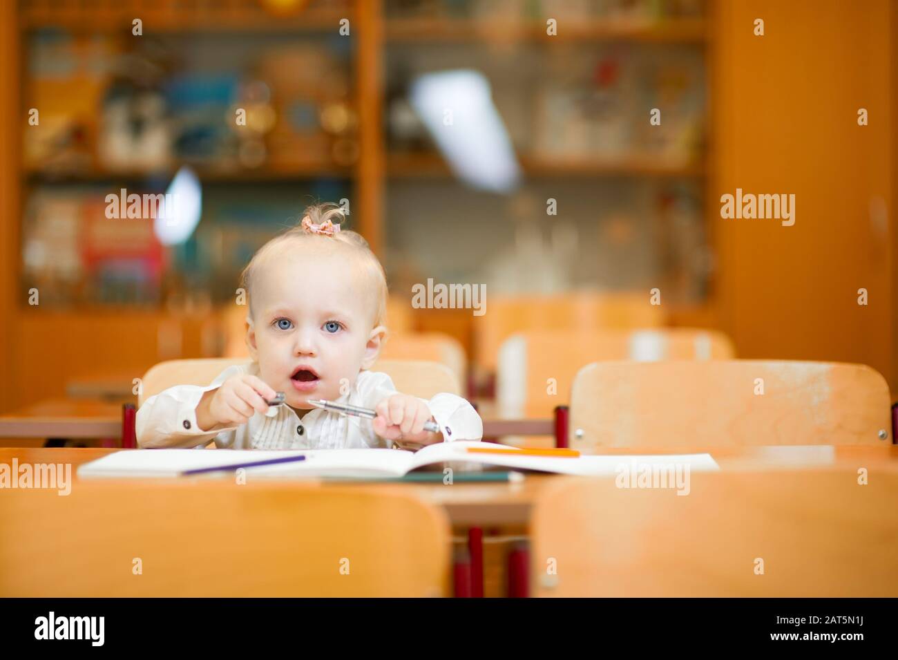 Little baby girl sitting at her desk at school Stock Photo - Alamy