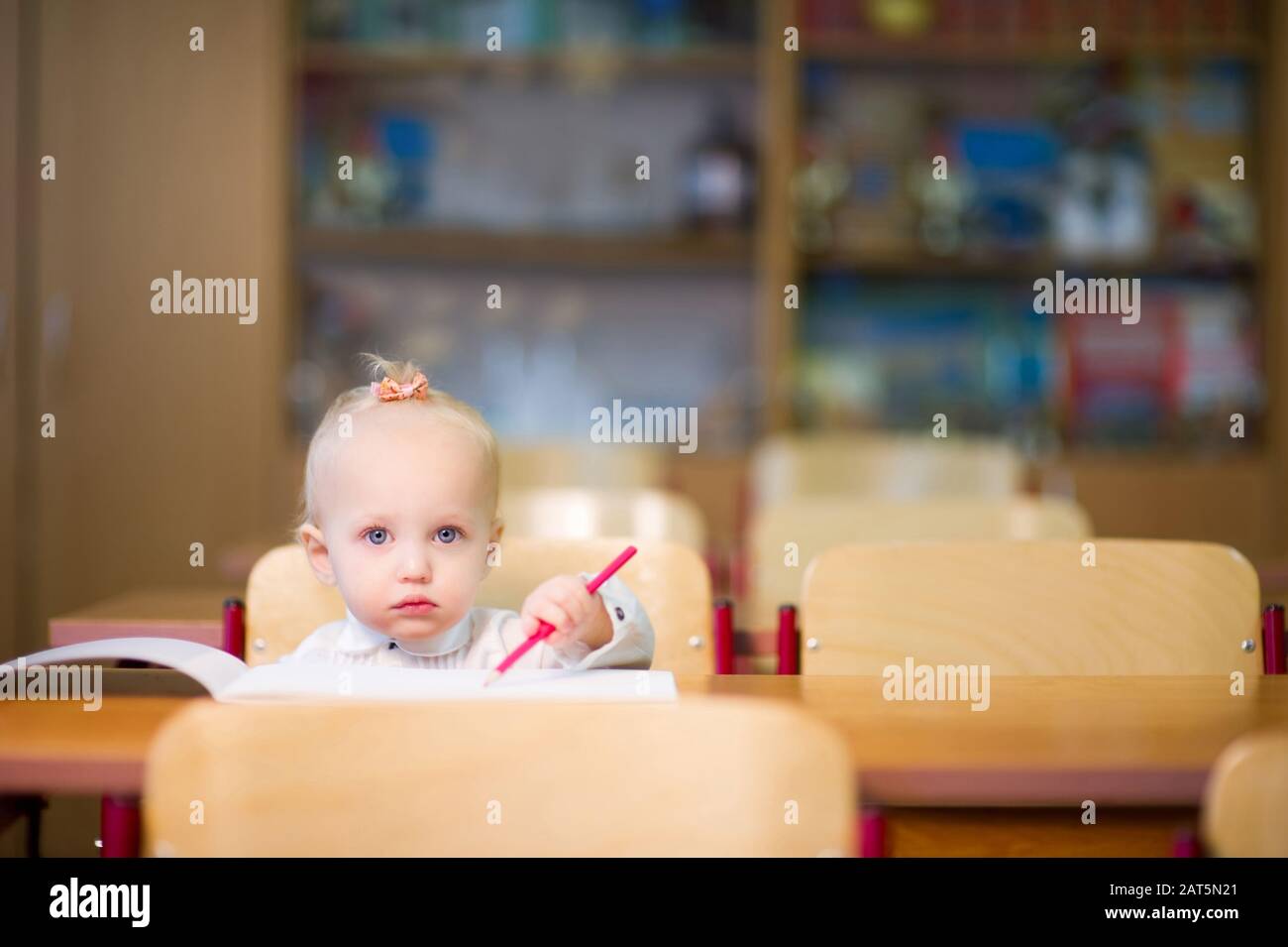 Little baby girl sitting at her desk at school Stock Photo - Alamy