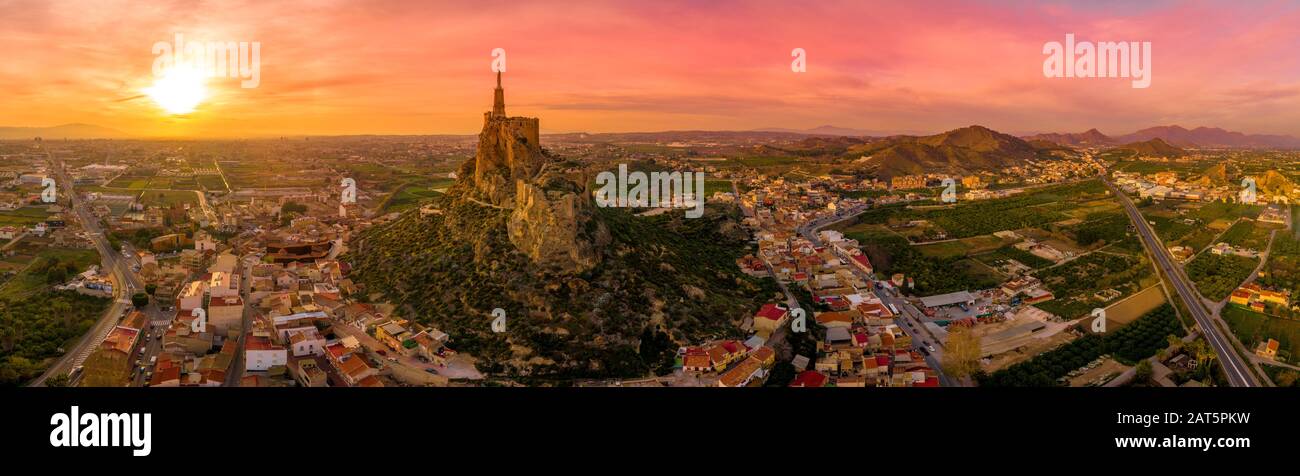 Monteagudo medieval castle ruin twelve rectangular towers circling the hilltop and the sacred heart of Jesus Christ statue on top near Murcia Spain Stock Photo
