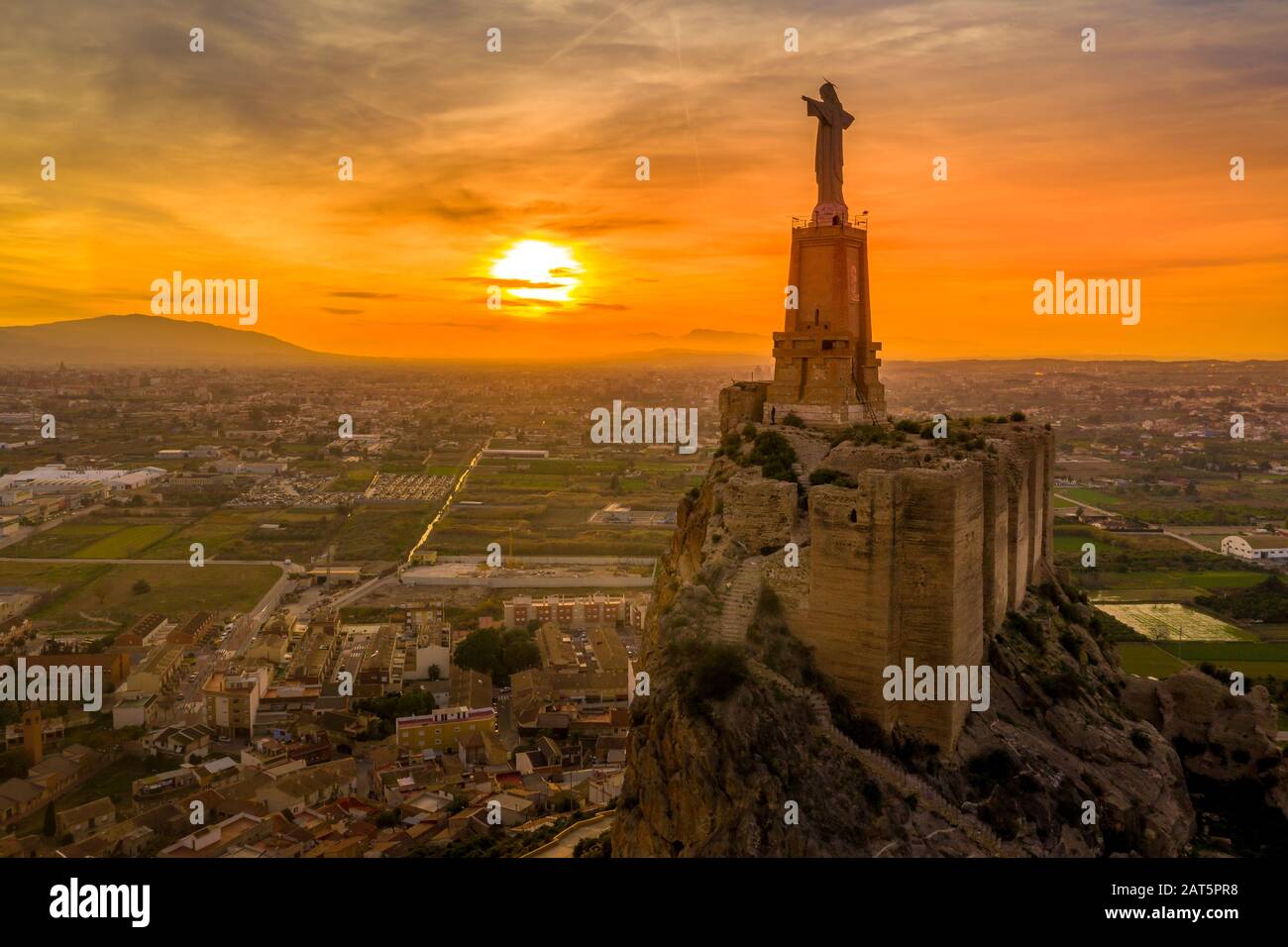 Monteagudo medieval castle ruin twelve rectangular towers circling the hilltop and the sacred heart of Jesus Christ statue on top near Murcia Spain Stock Photo