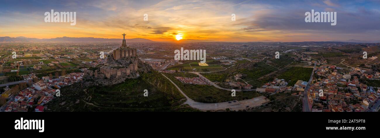 Monteagudo medieval castle ruin twelve rectangular towers circling the hilltop and the sacred heart of Jesus Christ statue on top near Murcia Spain Stock Photo