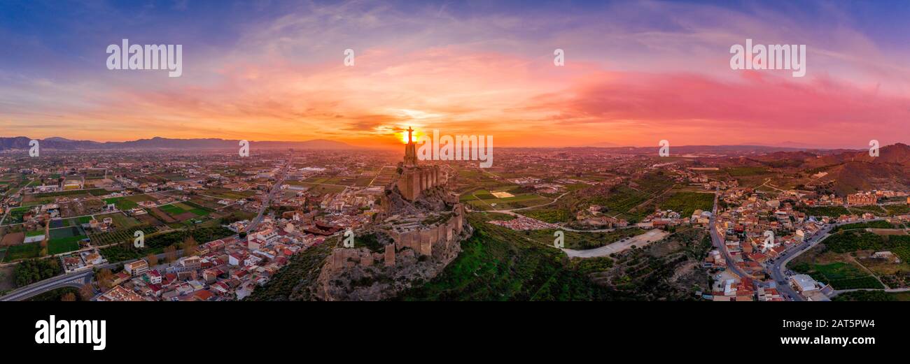 Monteagudo medieval castle ruin twelve rectangular towers circling the hilltop and the sacred heart of Jesus Christ statue on top near Murcia Spain Stock Photo