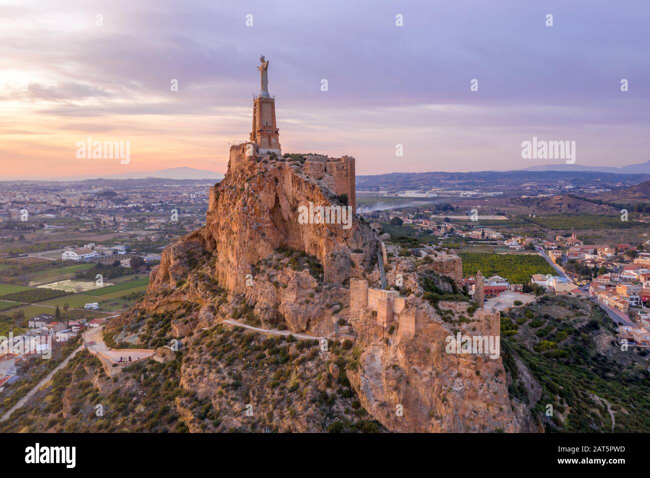 Monteagudo medieval castle ruin twelve rectangular towers circling the hilltop and the sacred heart of Jesus Christ statue on top near Murcia Spain Stock Photo
