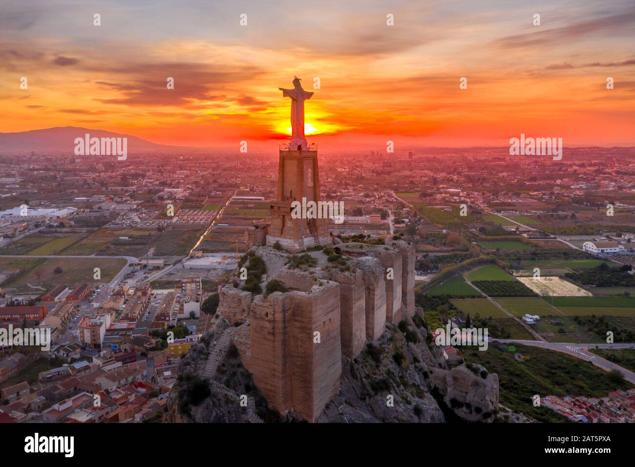 Monteagudo medieval castle ruin twelve rectangular towers circling the hilltop and the sacred heart of Jesus Christ statue on top near Murcia Spain Stock Photo