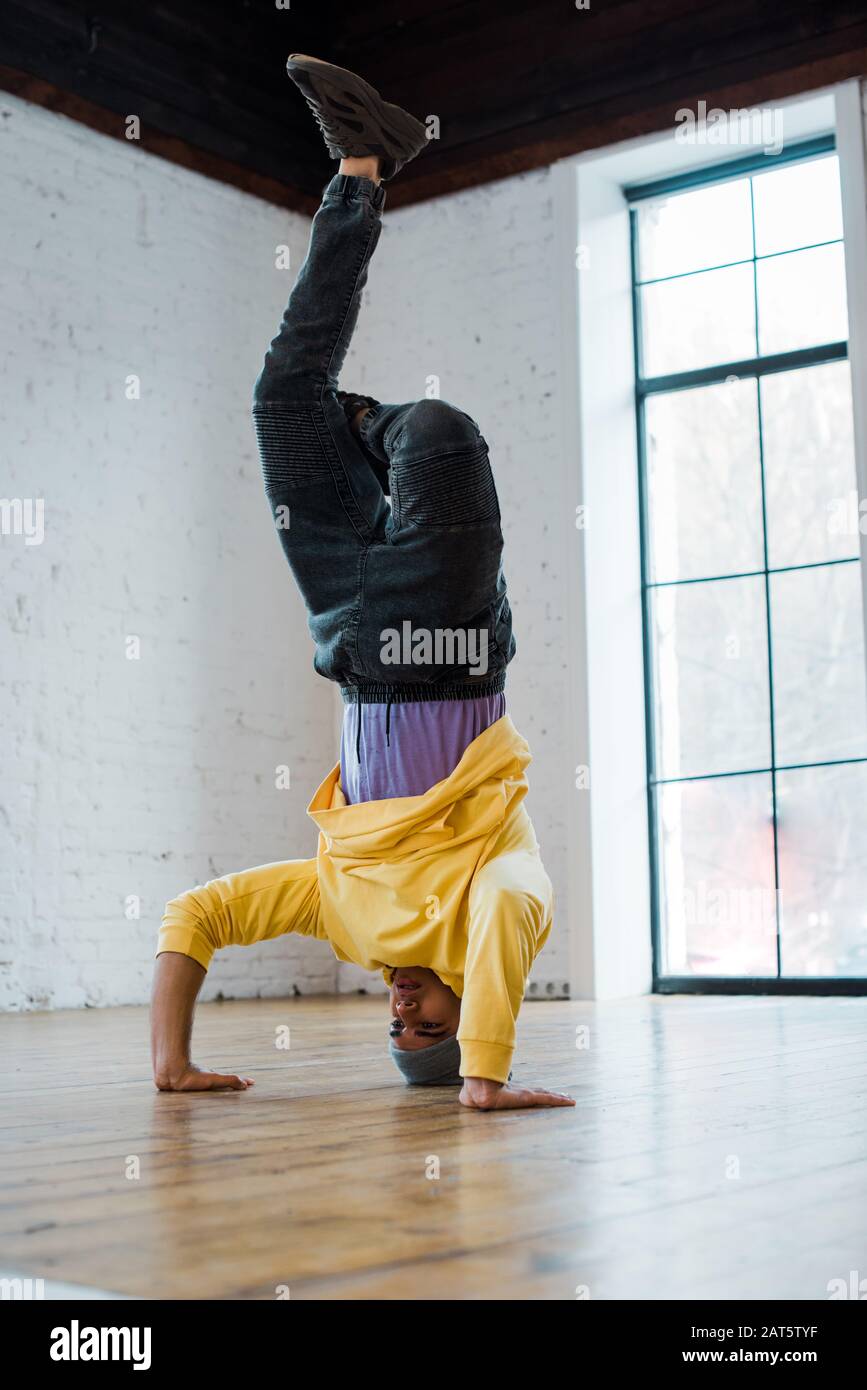 man in hat breakdancing and doing handstand in dance studio Stock Photo
