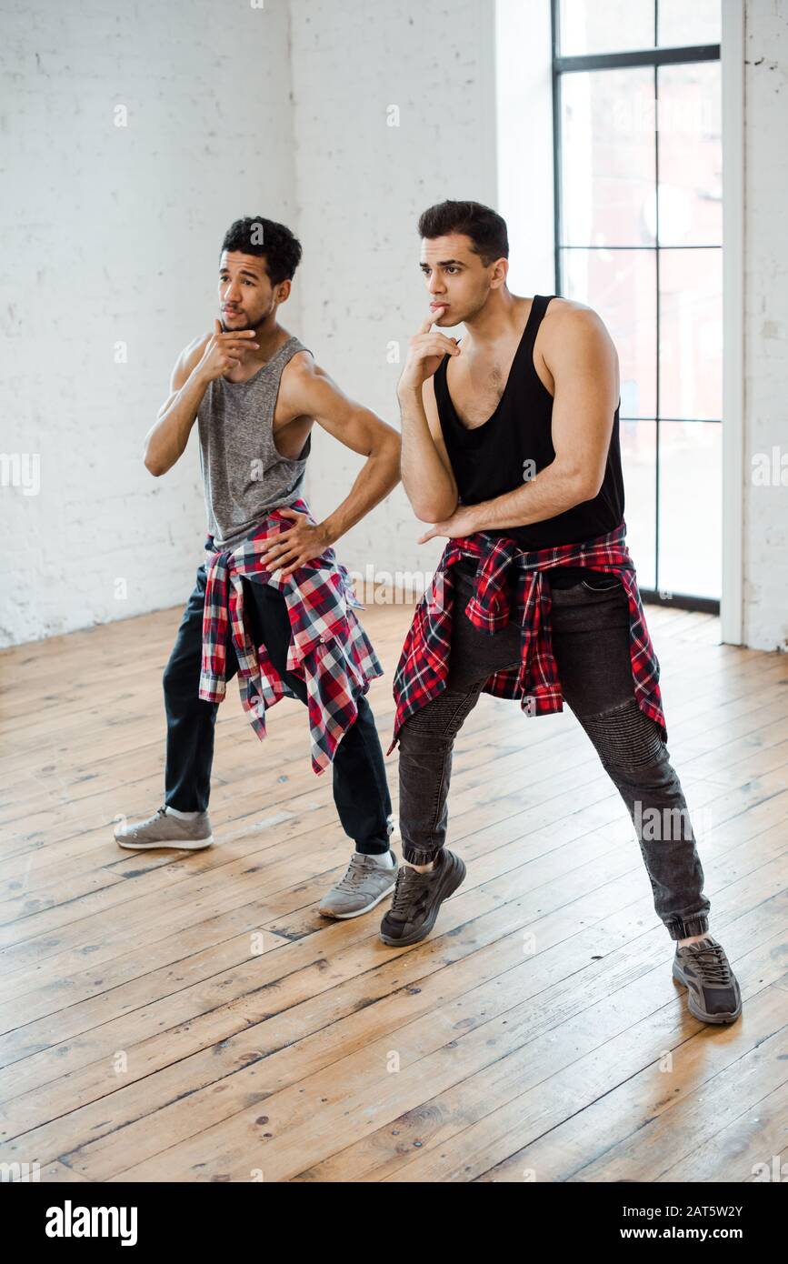 pensive multicultural dancers touching faces while posing in dance