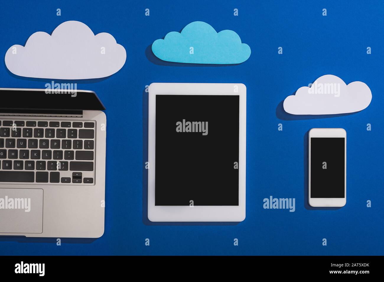 top view of empty paper clouds near laptop, smartphone and digital ...