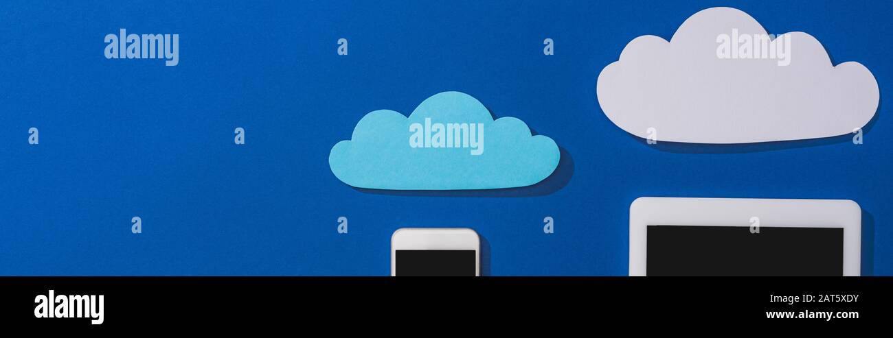 top view of empty paper clouds near smartphone and digital tablet with ...