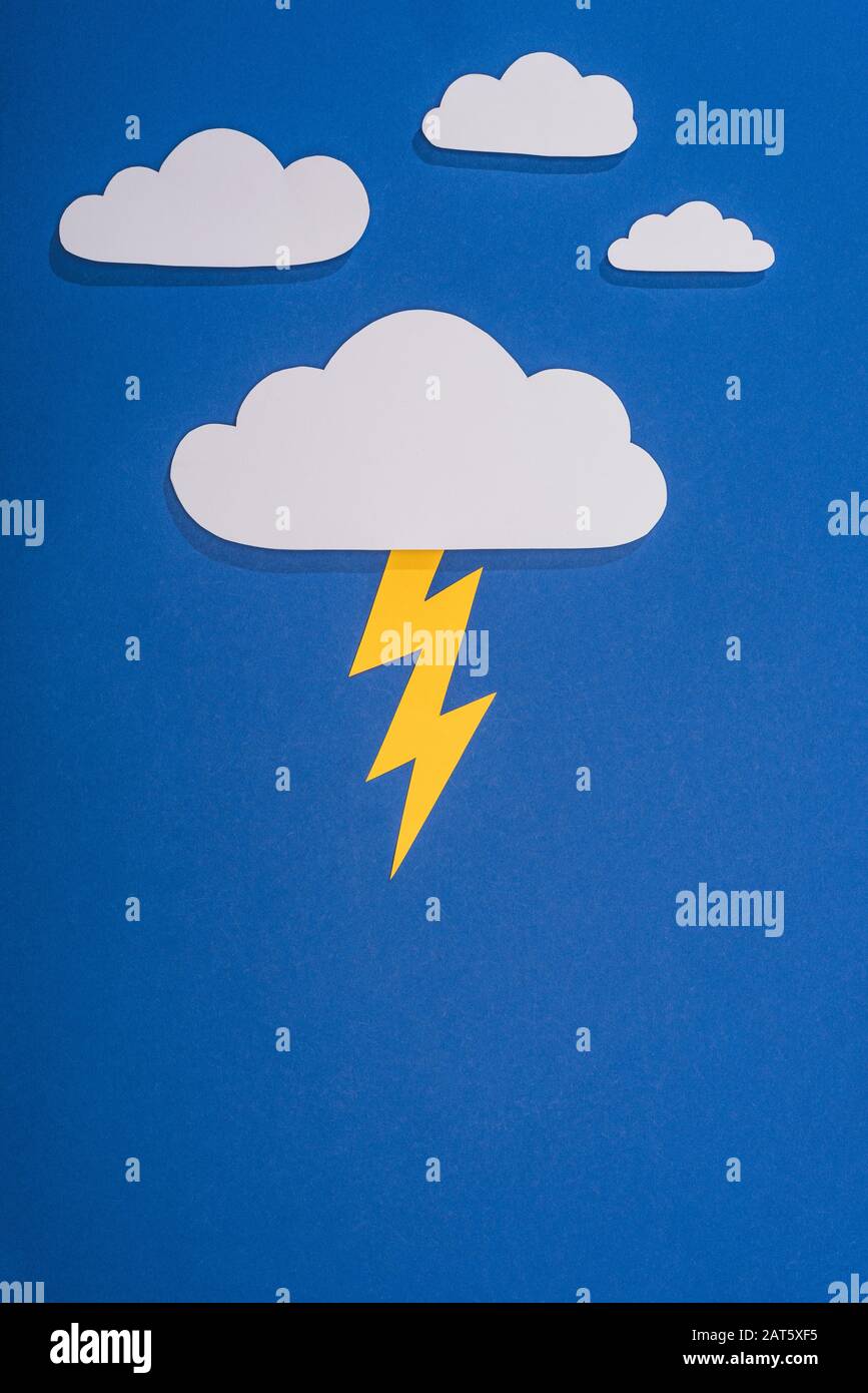 top view of white paper cut clouds with lighting on blue background ...