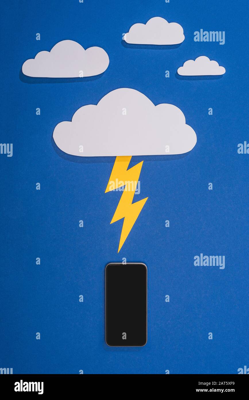 top view of white paper cut clouds with lighting hitting smartphone on ...
