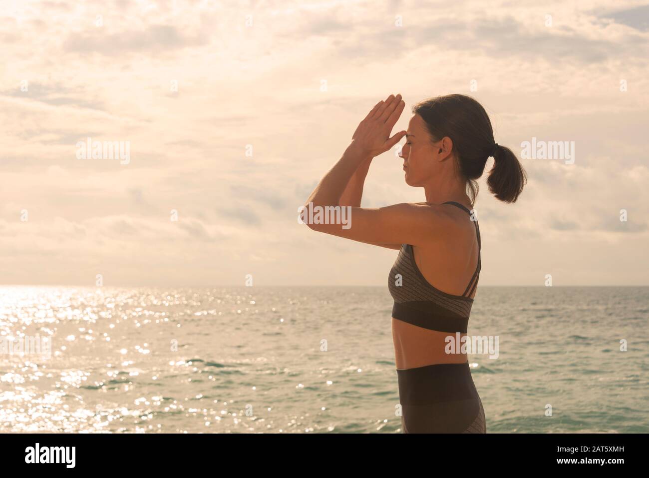 Woman Meditating by the ocean, Yoga Poses Prayer To The Third Eye Stock Photo