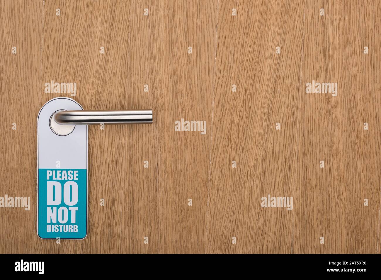 Wooden hotel room door with please do no disturb sign on handle stock