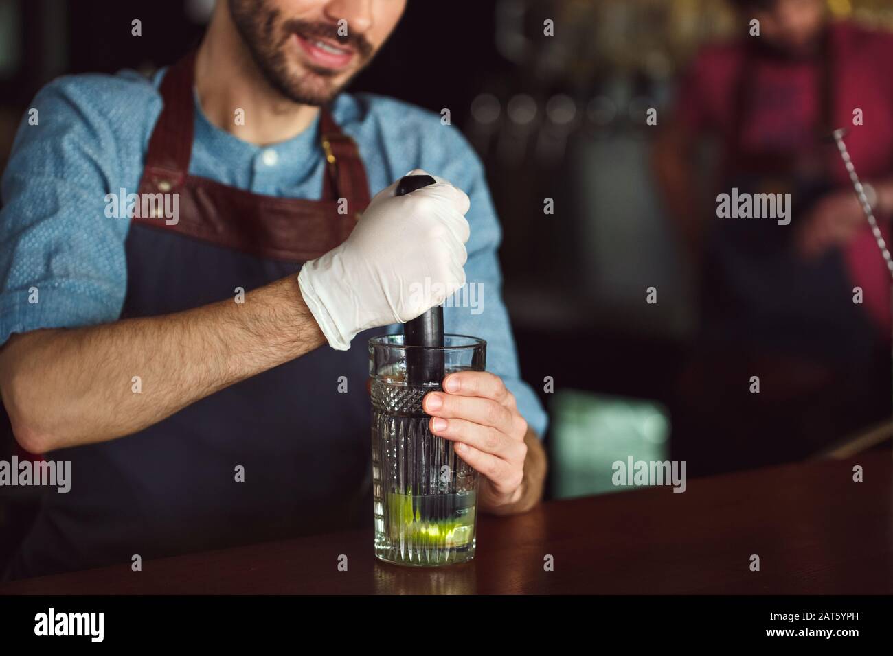 Drink Preparation. Bartender standing at counter squeezing out lime