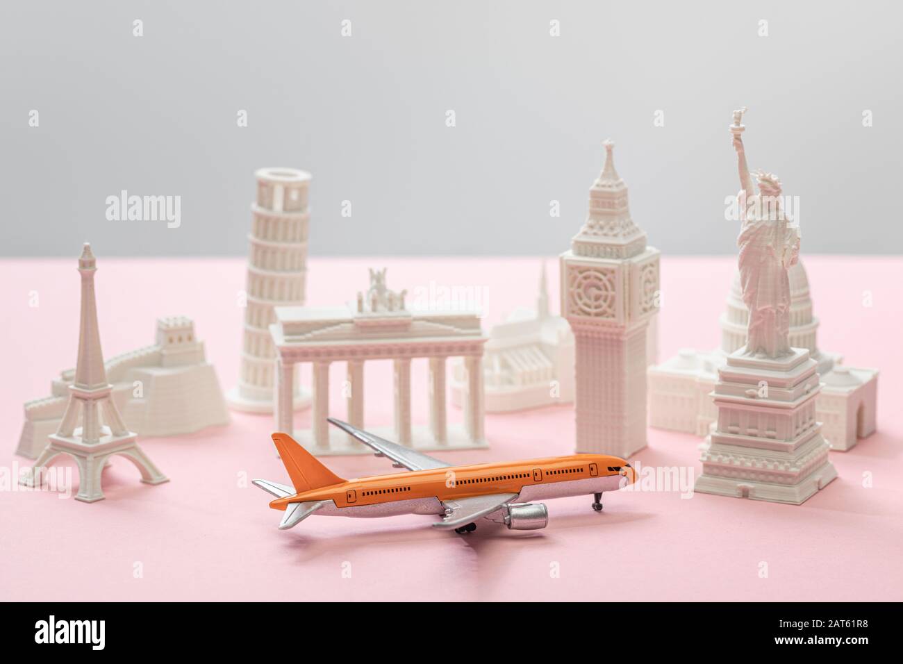 toy airplane near small statuettes of different countries on grey and pink Stock Photo