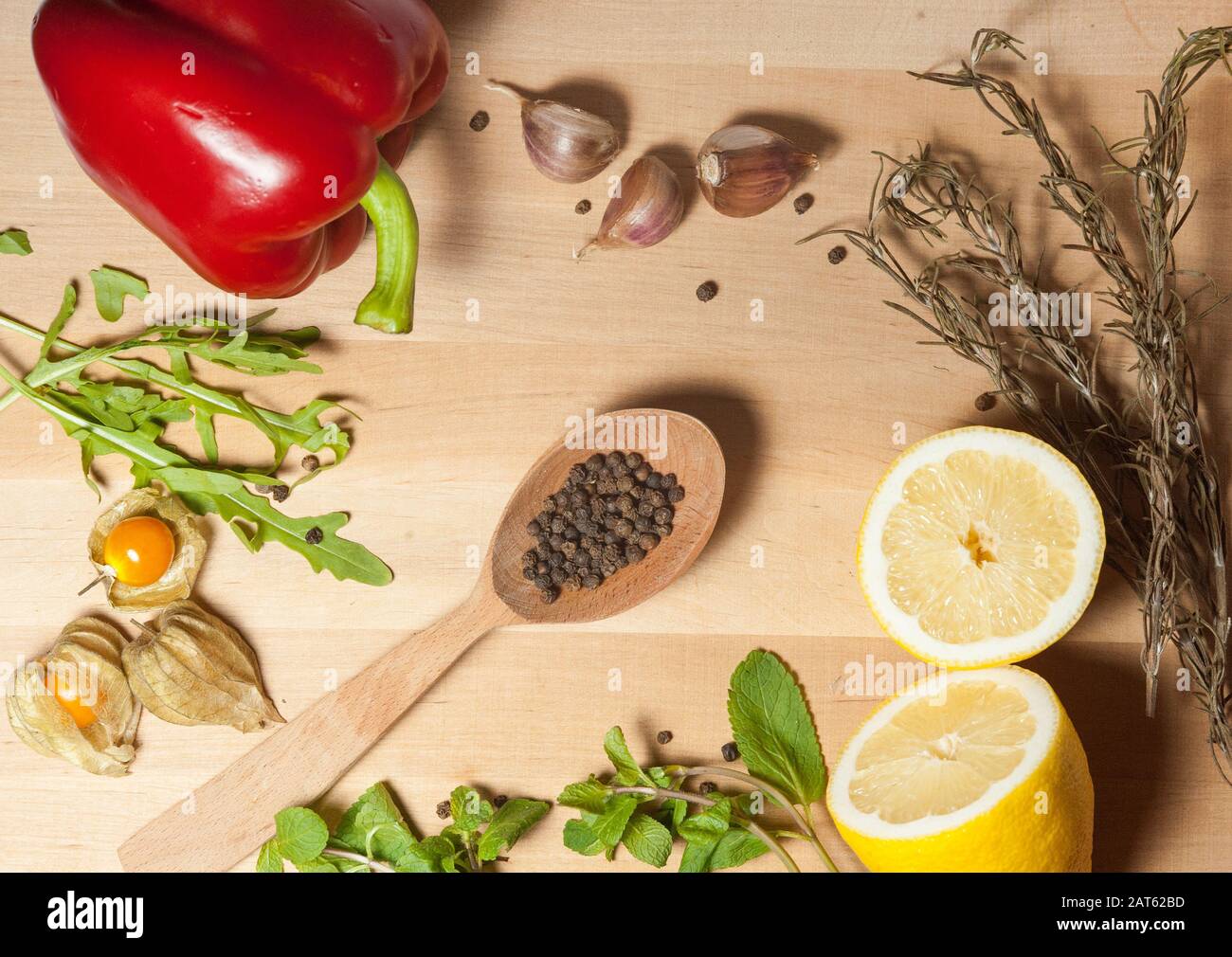 spices and vegetables on a wooden board with a bed in the center of the frame Stock Photo