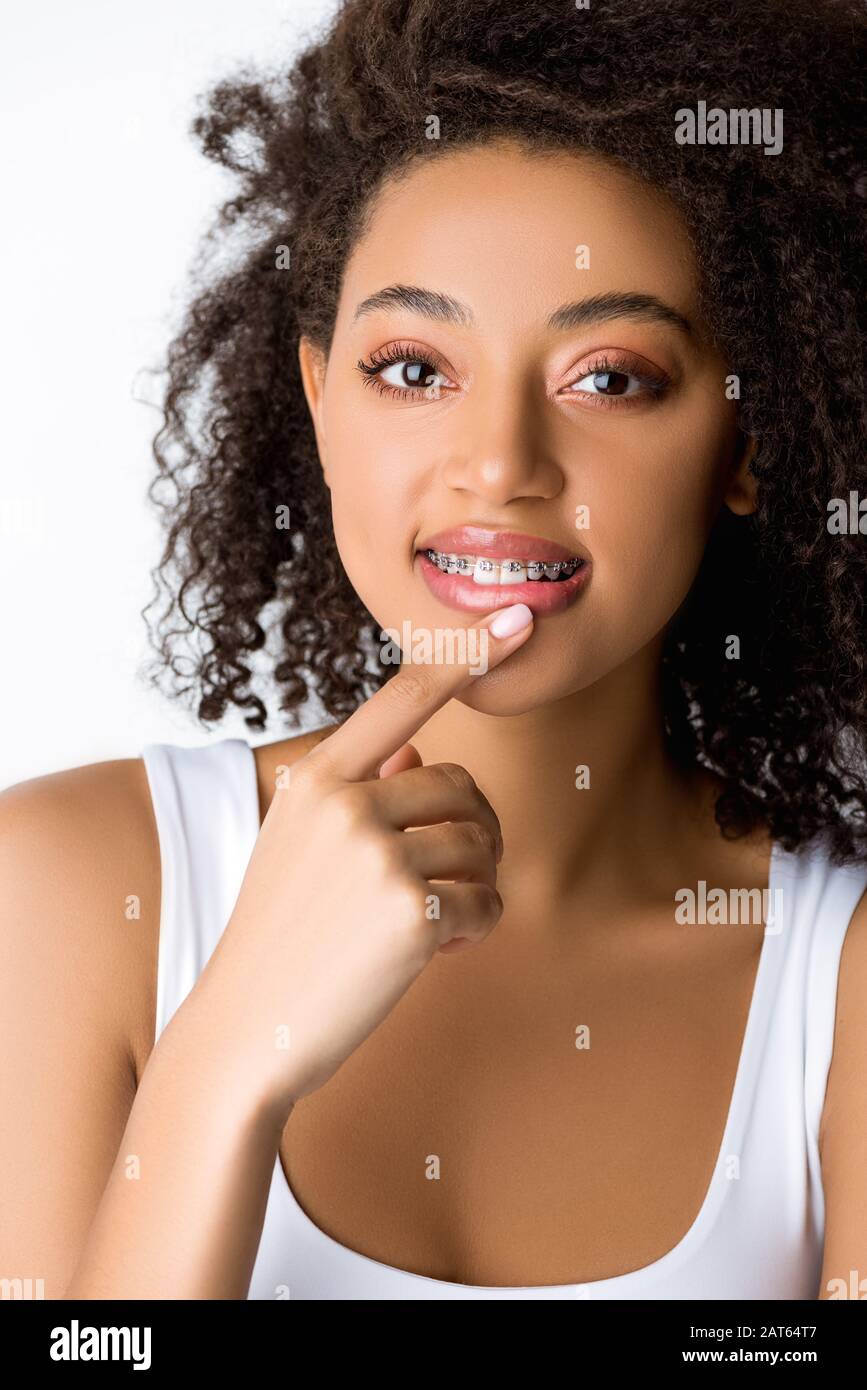 pensive smiling african american girl with dental braces touching lip