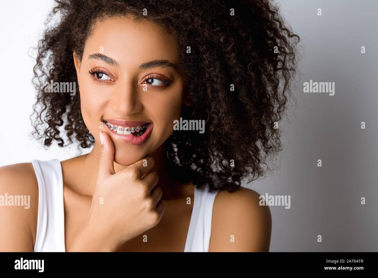 thoughtful smiling african american girl with dental braces touching