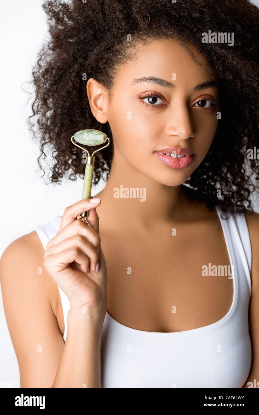 beautiful african american girl using stone facial roller, isolated on grey  Stock Photo - Alamy